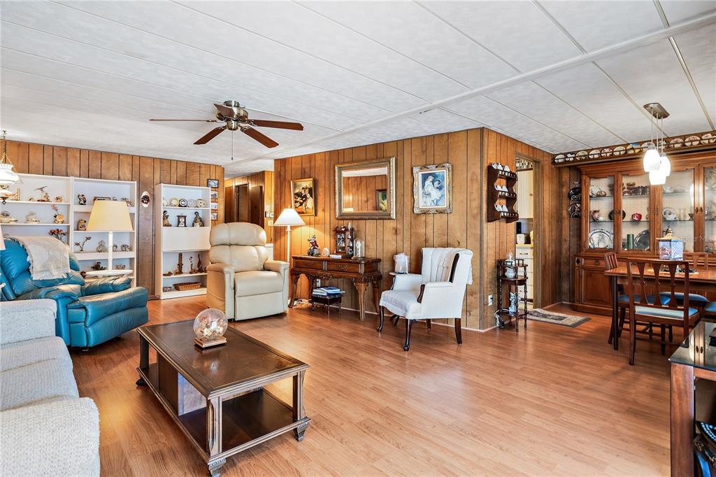 A living and dining area features wood-paneled walls, wood-look flooring, and a ceiling fan — 3410 SPANISH OAK TERRACE, SARASOTA, FL