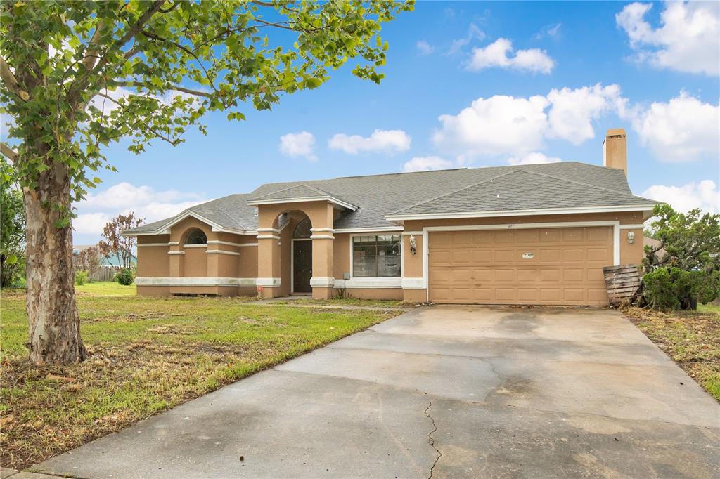 A single-story tan stucco house with a two-car garage and a concrete driveway — 3210 PELL MELL DRIVE, ORLANDO, FL