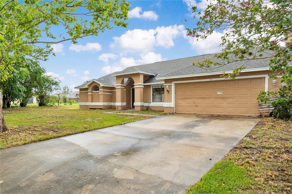 A tan, single-story house with a concrete driveway and an arched entryway — 3210 PELL MELL DRIVE, ORLANDO, FL