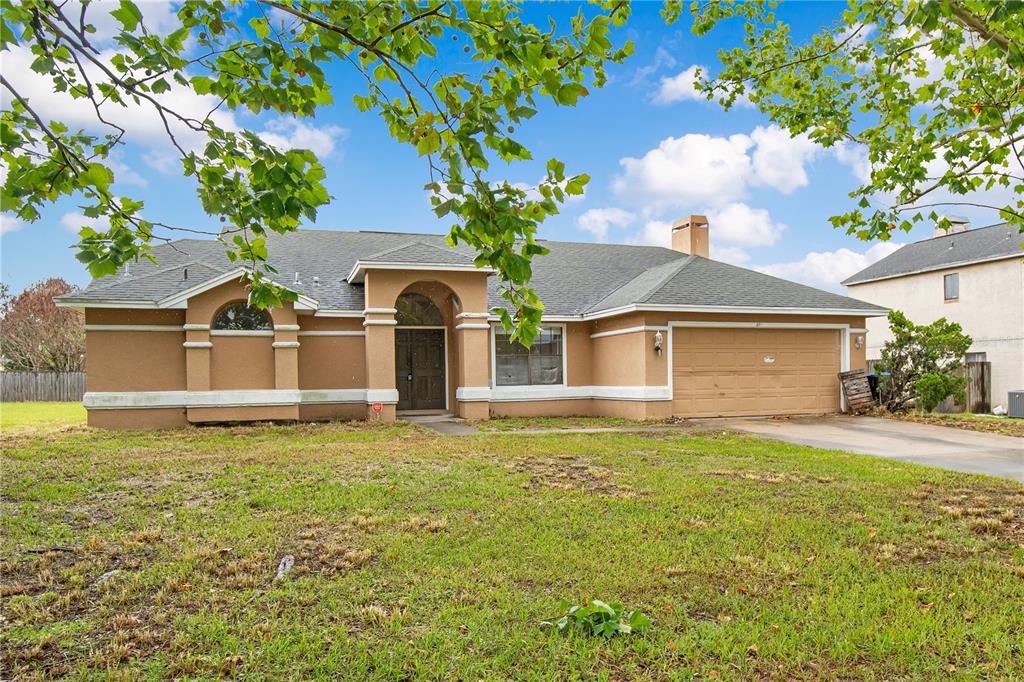A single-story tan stucco house with a two-car garage and an arched entryway — 3210 PELL MELL DRIVE, ORLANDO, FL