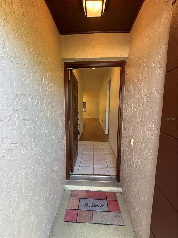 An open front door reveals a tiled entryway leading into a home with wood flooring — 5911 N FORK COURT, LAKELAND, FL