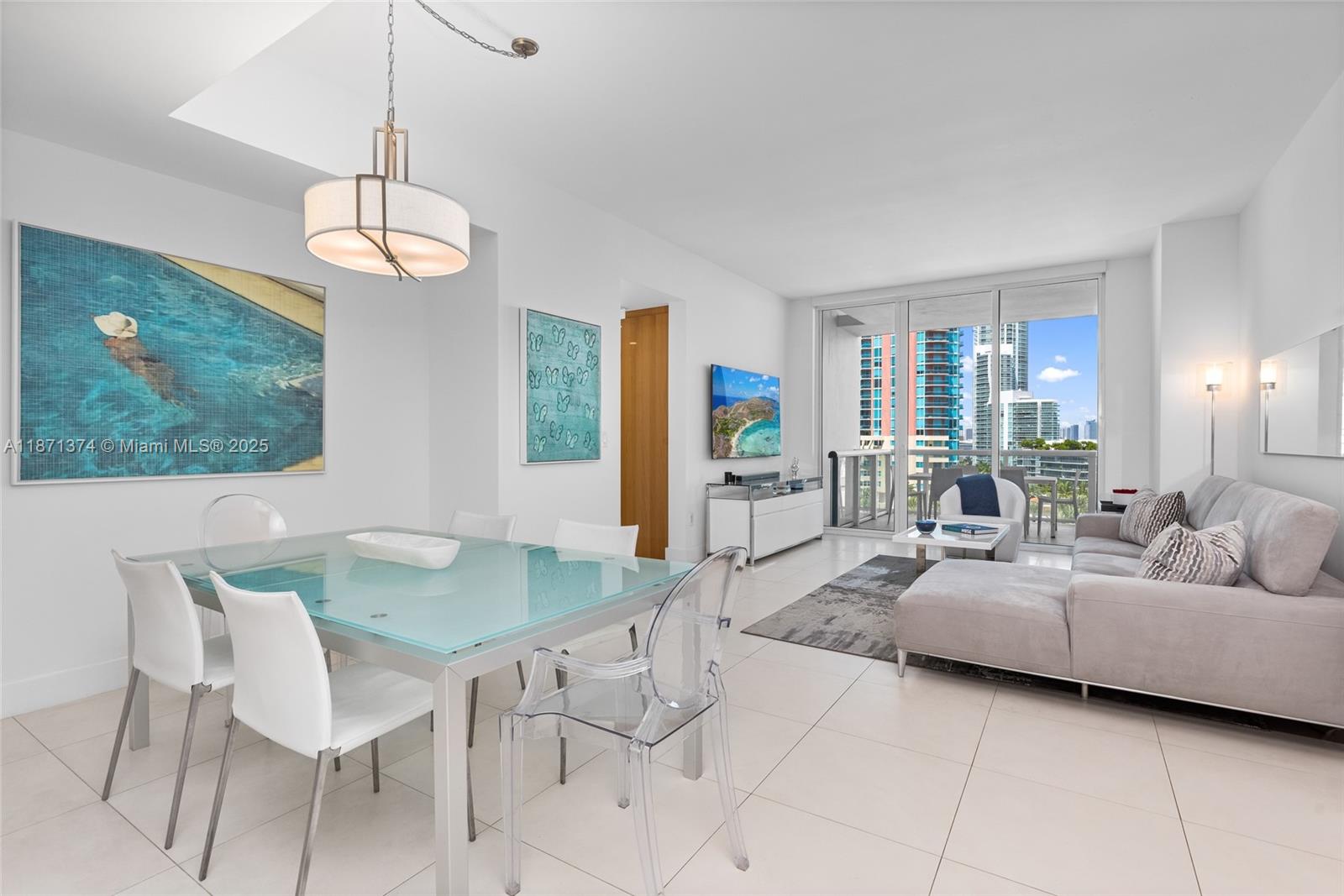 A modern living and dining area features white tile floors, glass furniture, and balcony views — 50 S Pointe Dr # 1005, Miami Beach FL 33139, MIAMI BEACH, FL