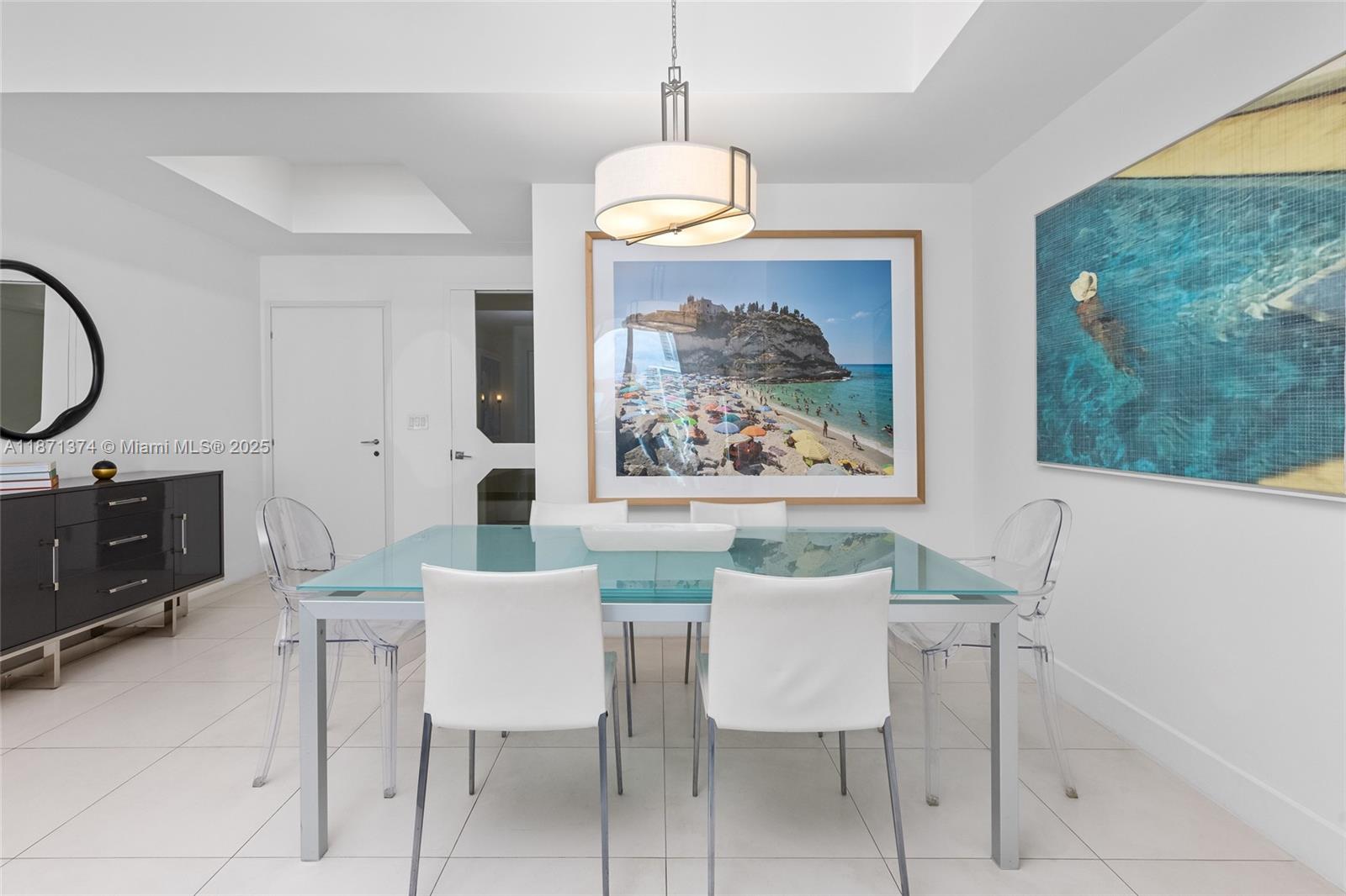 A dining room features a glass-top table, white chairs, clear acrylic chairs, and wall art — 50 S Pointe Dr # 1005, Miami Beach FL 33139, MIAMI BEACH, FL