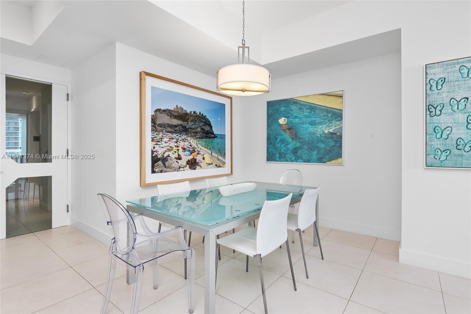 A dining area features a glass-top table, four chairs, and three framed wall art pieces — 50 S Pointe Dr # 1005, Miami Beach FL 33139, MIAMI BEACH, FL