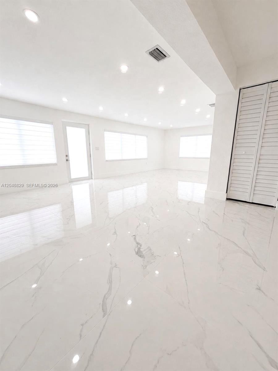 A bright, empty room features white marble-look tile flooring and recessed ceiling lighting — 2390 Service Rd, Opa-Locka FL 33054, OPA-LOCKA, FL