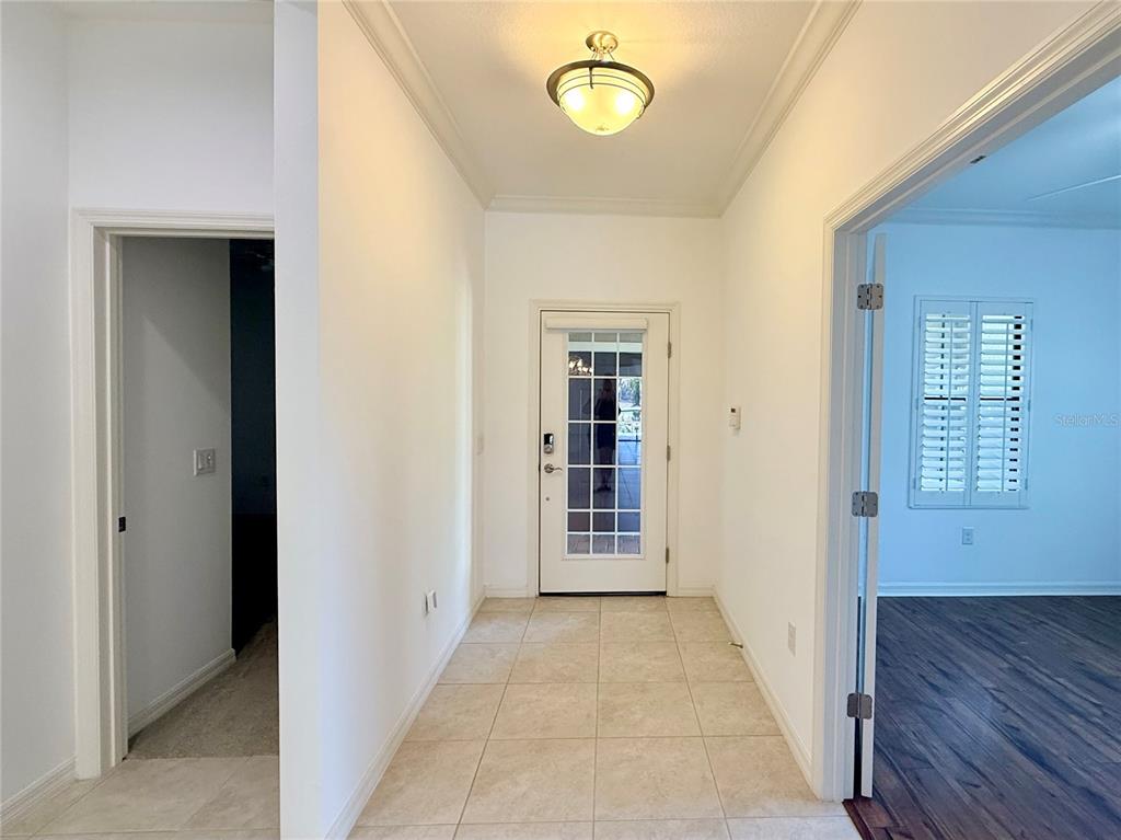 A tiled entryway features a glass-paneled door, a ceiling light, and adjacent room doorways — 10735 TROPHY DRIVE, ENGLEWOOD, FL