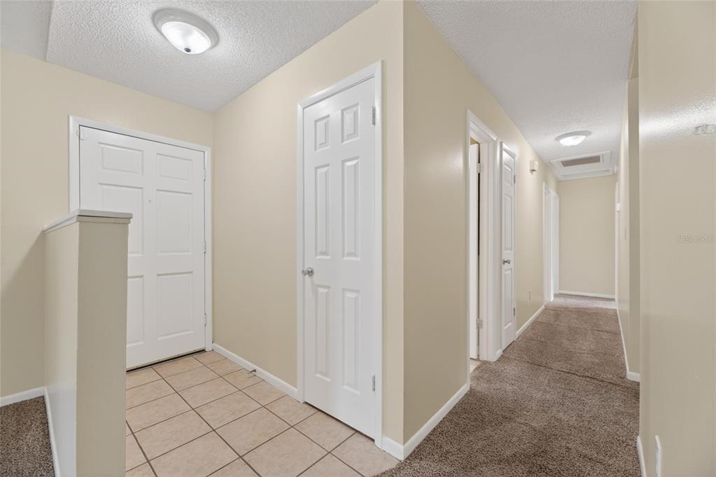 An entryway with tiled flooring leads to a carpeted hallway with several white interior doors — 5001 WHITEWAY DRIVE, TAMPA, FL