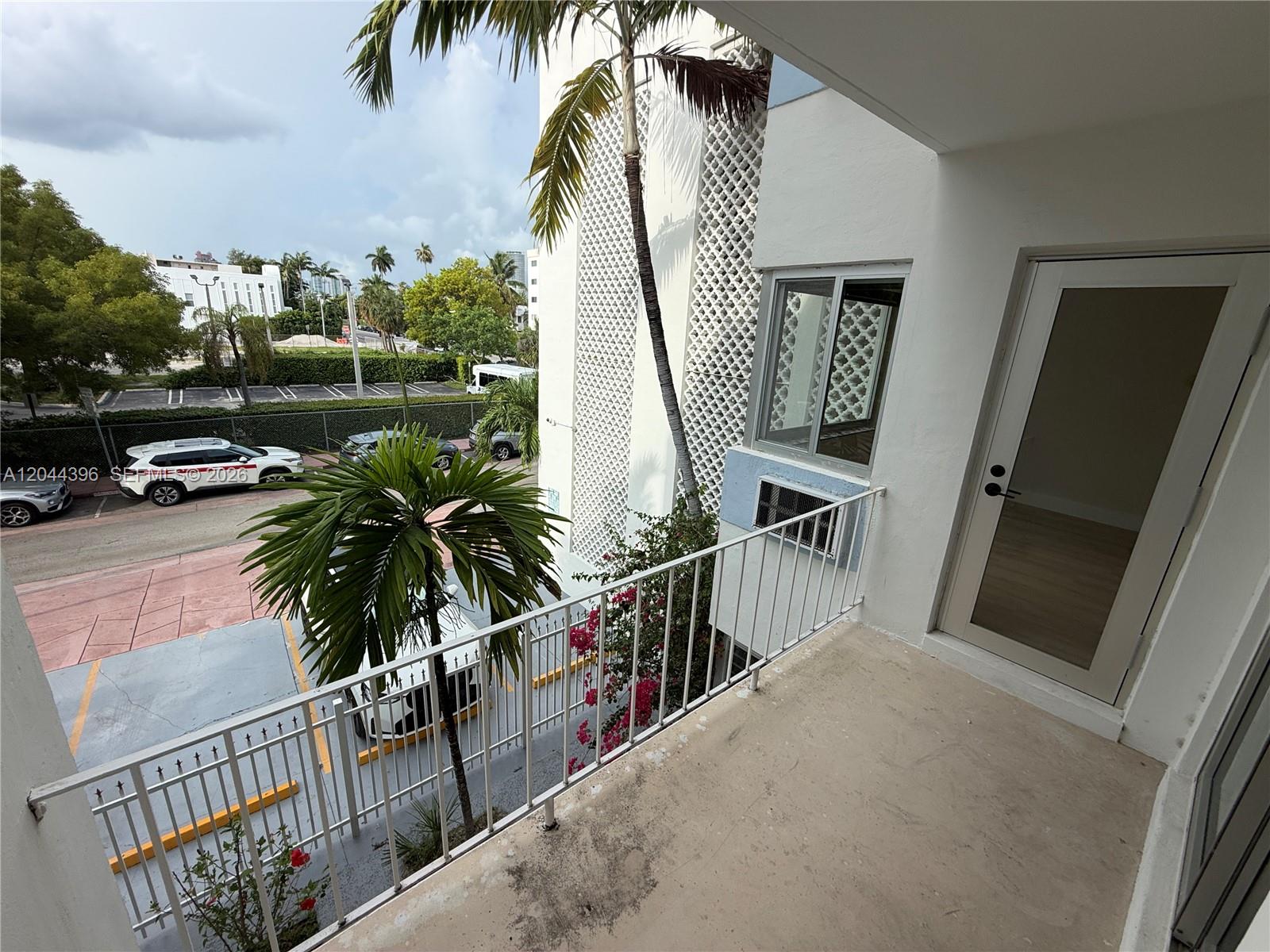 A balcony with a white metal railing overlooks a parking lot and palm trees — 641 Espanola Way # 17, Miami Beach FL 33139, MIAMI BEACH, FL