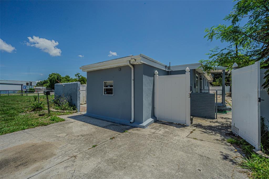 A gray exterior wall with a window and a white vinyl gate on a driveway — 1627 28TH STREET N, ST PETERSBURG, FL