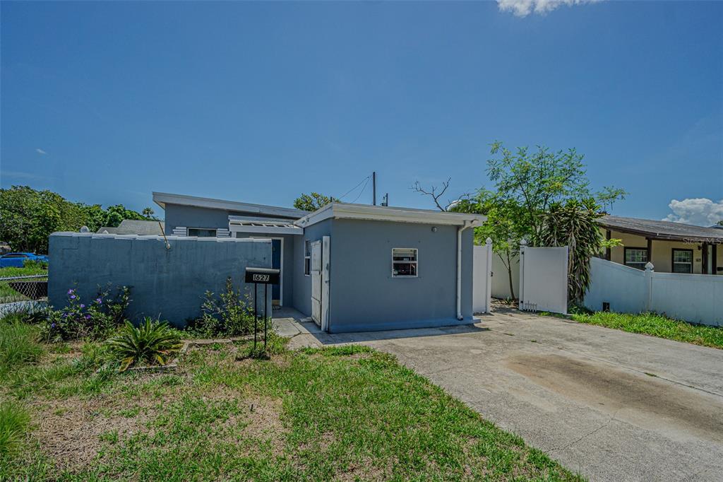 A single-story gray house features a concrete driveway, a front wall, and a mailbox — 1627 28TH STREET N, ST PETERSBURG, FL