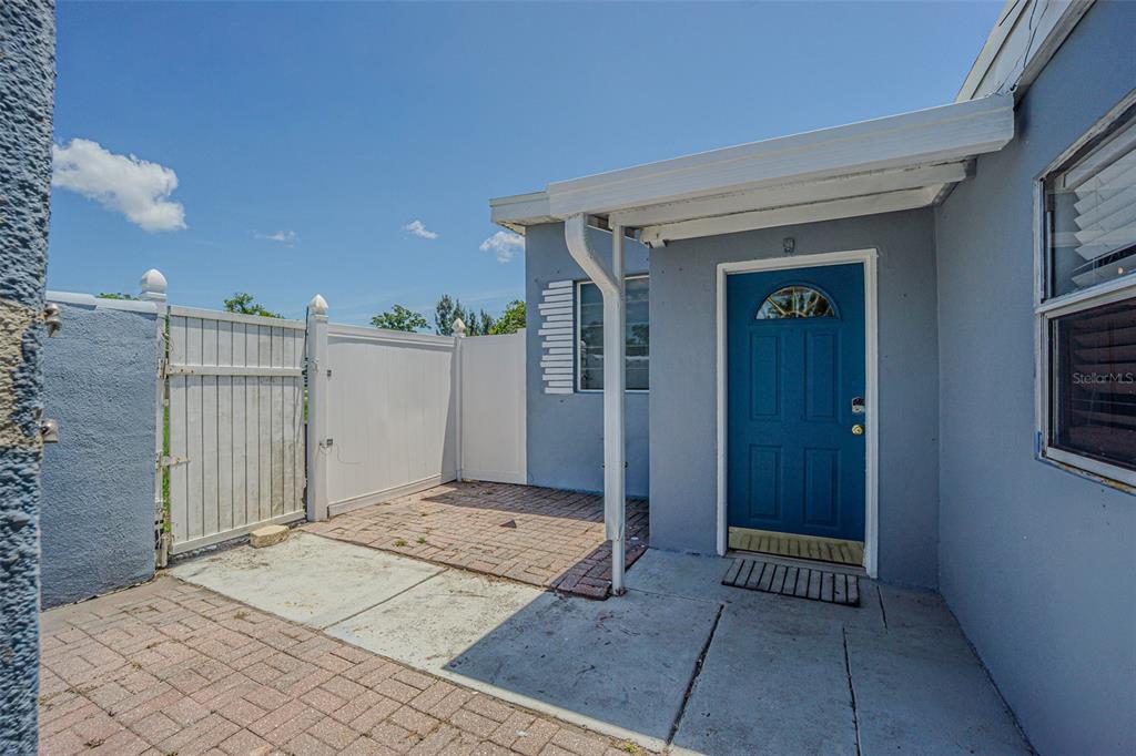 A blue front door opens onto a paved patio area enclosed by a white vinyl fence — 1627 28TH STREET N, ST PETERSBURG, FL