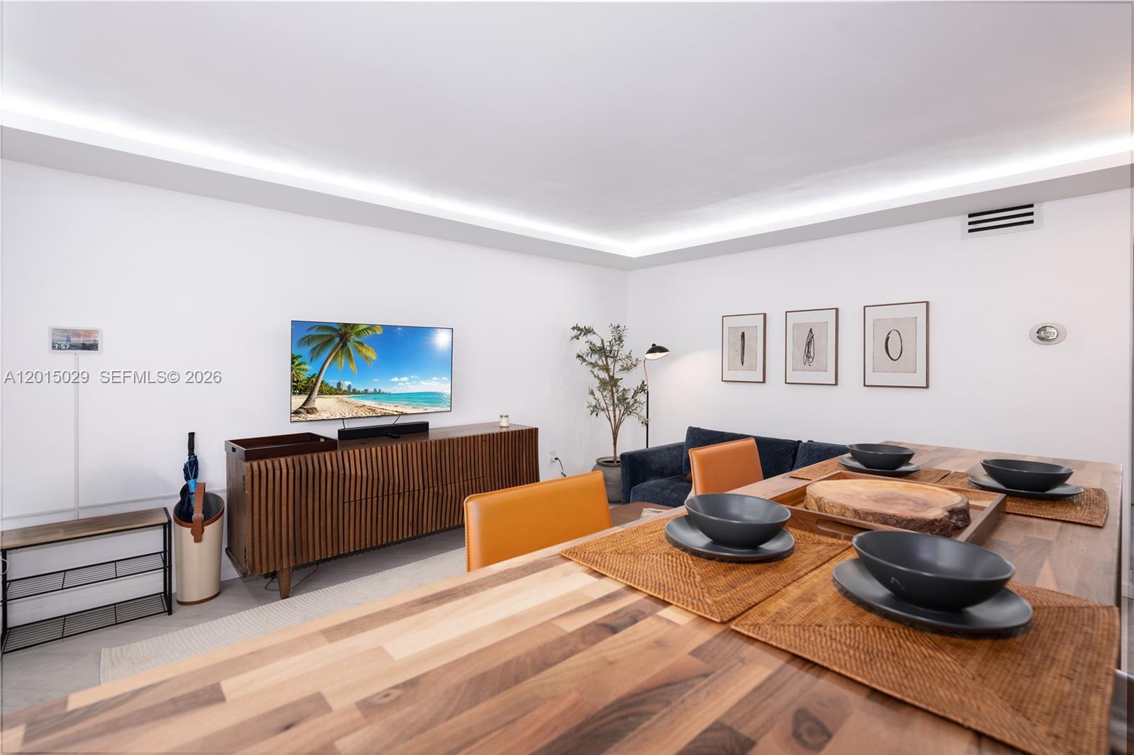 A dining area with a wooden table and chairs sits before a living room space — 525 Meridian Ave # 203, Miami Beach FL 33139, MIAMI BEACH, FL