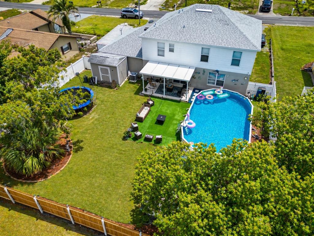 An aerial view of a backyard featuring a swimming pool, patio, and trampoline — 3483 CHARMWOOD AVENUE, SPRING HILL, FL