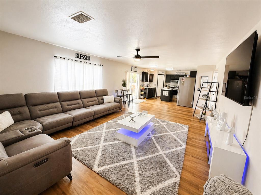 A living room with a large gray sectional, a white coffee table, and wood flooring — 3483 CHARMWOOD AVENUE, SPRING HILL, FL