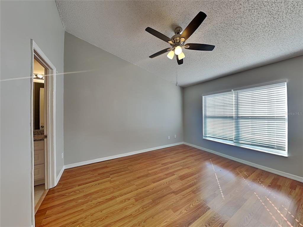 An empty bedroom features wood-look flooring, a ceiling fan, and a window with white blinds — 17128 WOODCREST WAY, CLERMONT, FL