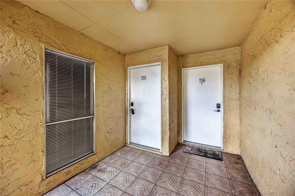 An exterior entryway features two white doors numbered 255 and 256 with tiled flooring — 3457 CLARK ROAD UNIT 255, SARASOTA, FL