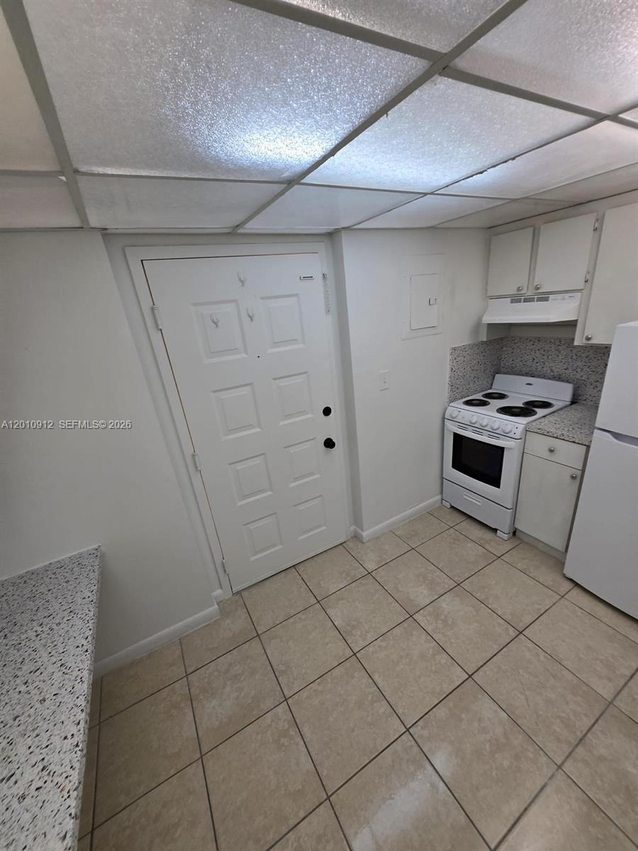 A small kitchen features white cabinets, a white stove, and light-colored tile flooring — 6980 NW 186th St # 227A, Hialeah FL 33015, HIALEAH, FL