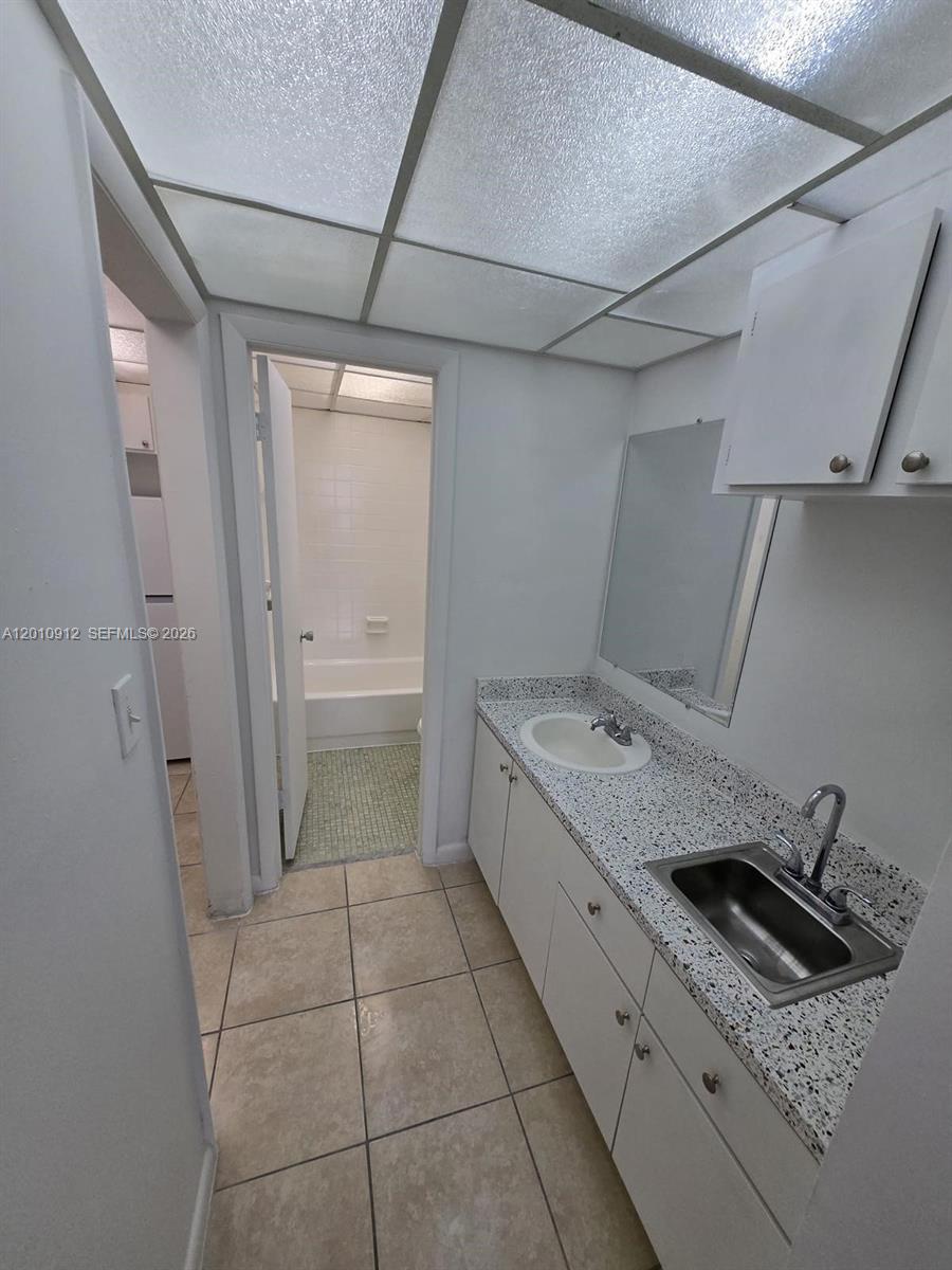A bathroom features a double-sink vanity with speckled countertops and a separate tub area — 6980 NW 186th St # 227A, Hialeah FL 33015, HIALEAH, FL