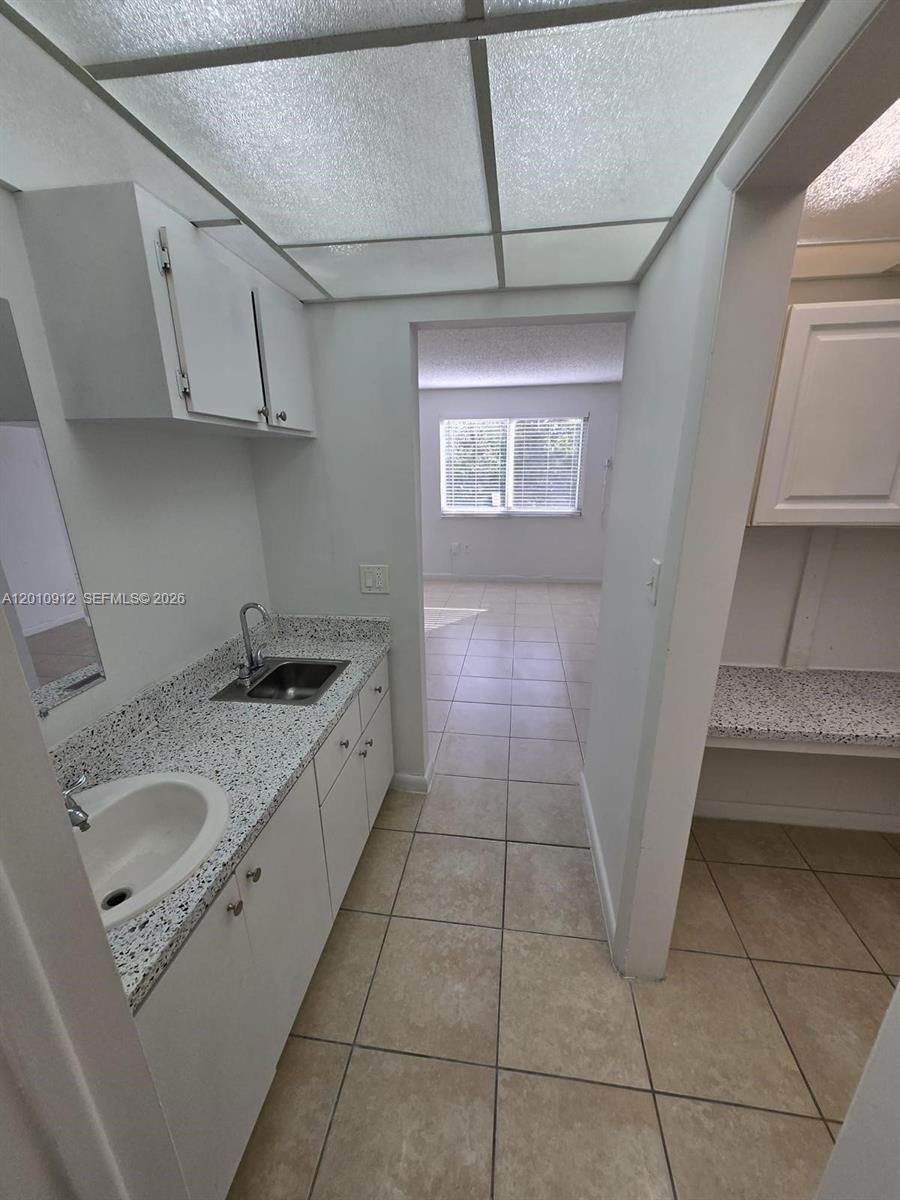 A small kitchen area features white cabinets, speckled countertops, and a drop-in sink — 6980 NW 186th St # 227A, Hialeah FL 33015, HIALEAH, FL