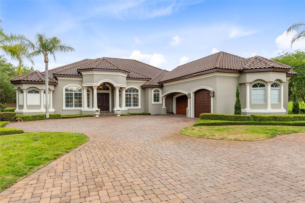 A single-story house with a tiled roof, beige stucco exterior, and a brick paver driveway — 1900 LAKE MARKHAM PRESERVE TRAIL, SANFORD, FL