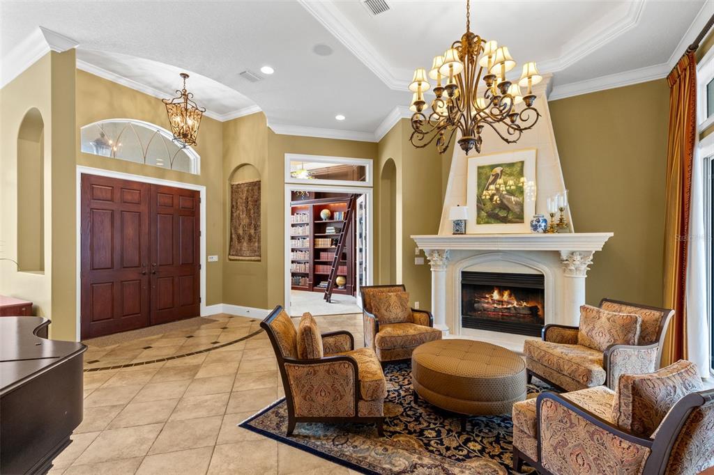 A formal living room features a fireplace, chandelier, patterned armchairs, and a tiled floor — 1900 LAKE MARKHAM PRESERVE TRAIL, SANFORD, FL
