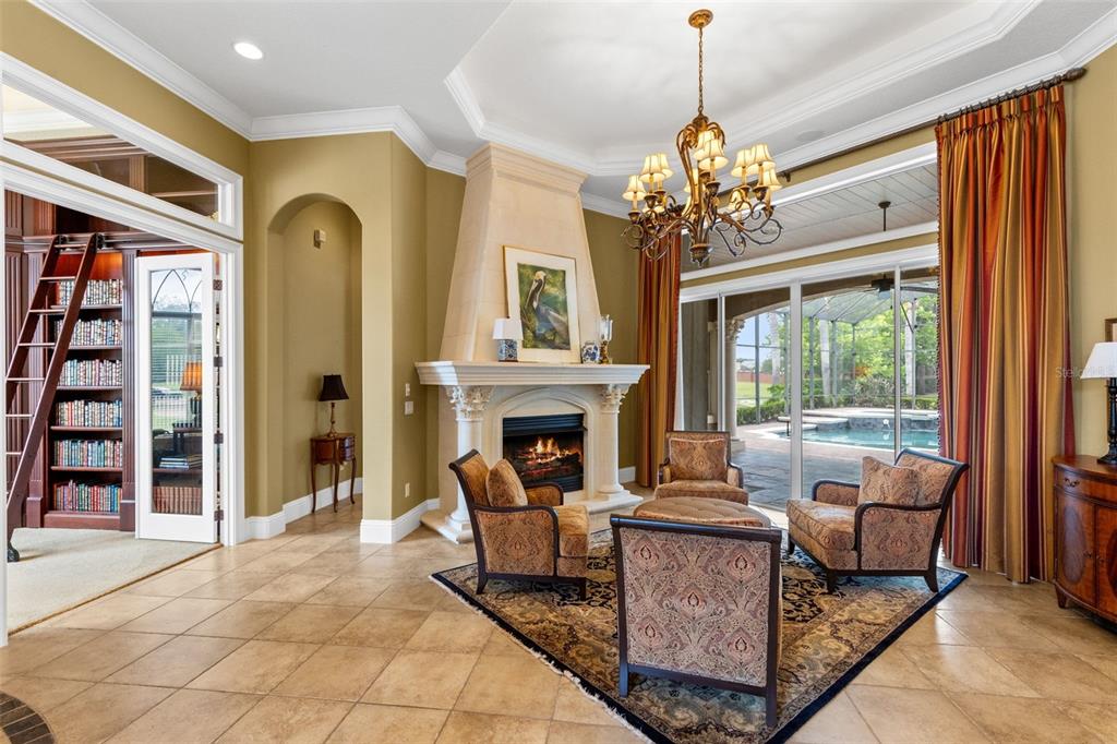 A living room features a stone fireplace, tile flooring, a chandelier, and sliding glass doors — 1900 LAKE MARKHAM PRESERVE TRAIL, SANFORD, FL