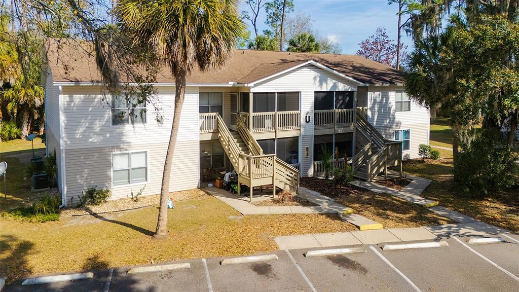 A two-story apartment building with tan siding, screened balconies, and wooden staircases — 1600 BIG TREE ROAD UNIT U7, SOUTH DAYTONA, FL