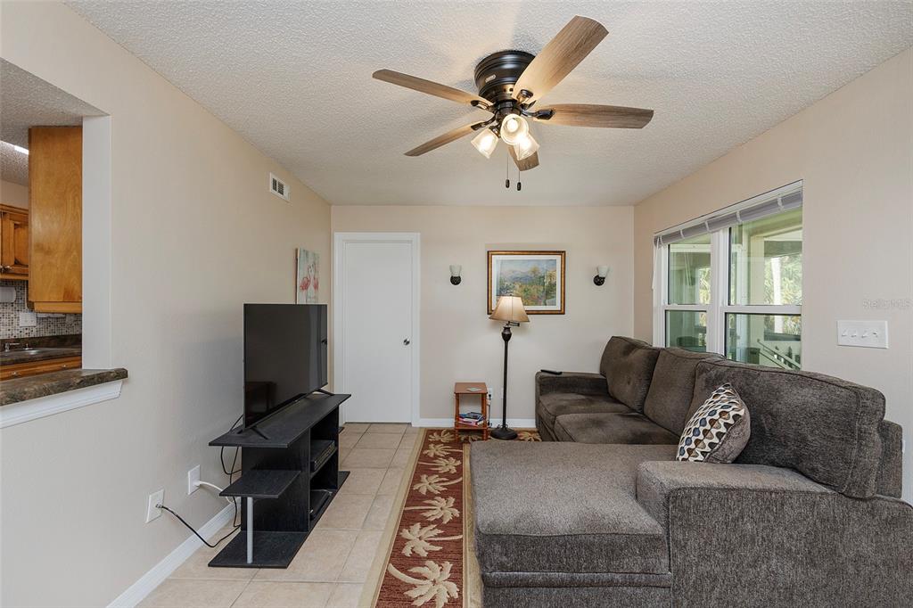 A living room features a sectional sofa, a television on a stand, and a ceiling fan — 1600 BIG TREE ROAD UNIT U7, SOUTH DAYTONA, FL