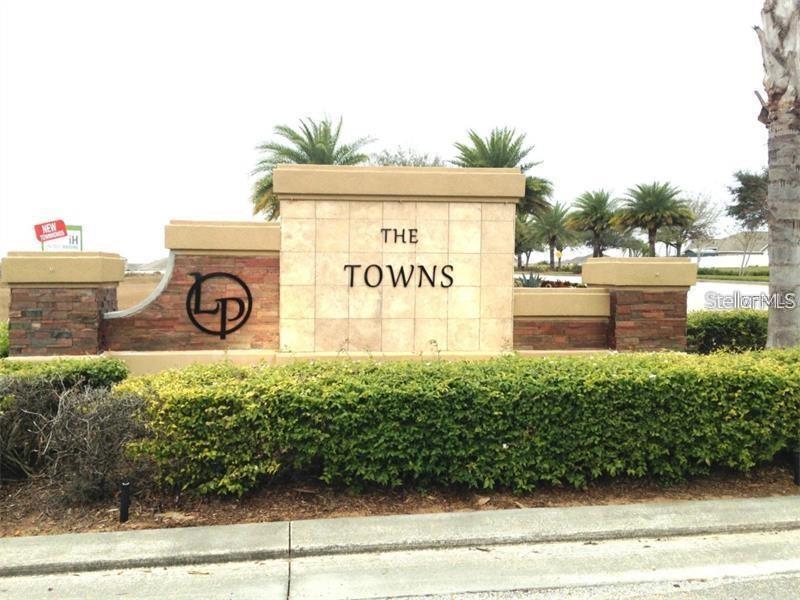 A stone and stucco monument sign for The Towns stands behind a manicured hedge — 765 CHELSEA DRIVE, DAVENPORT, FL