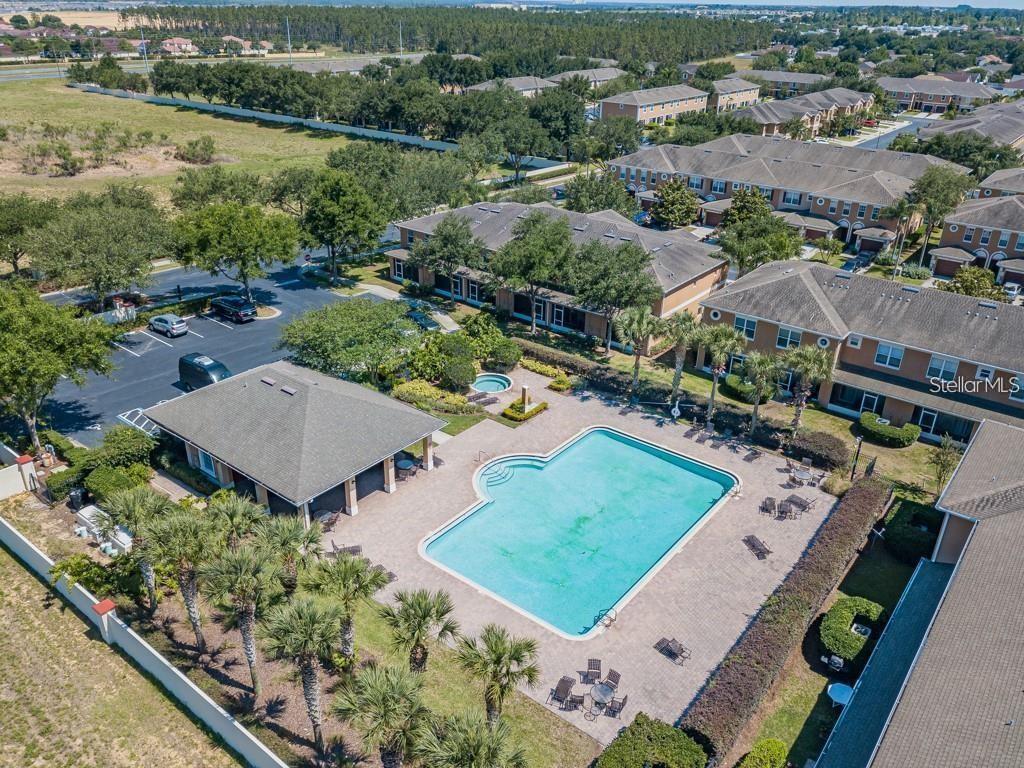 An aerial view shows a community swimming pool, clubhouse, and surrounding residential townhomes — 765 CHELSEA DRIVE, DAVENPORT, FL