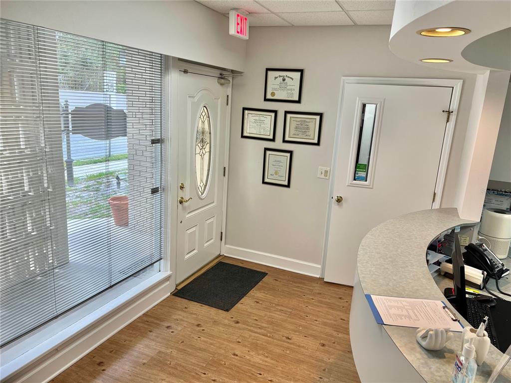 A reception area features a curved desk, wood-look flooring, a white entry door, and framed certificates — 2210 S MACDILL AVENUE, TAMPA, FL