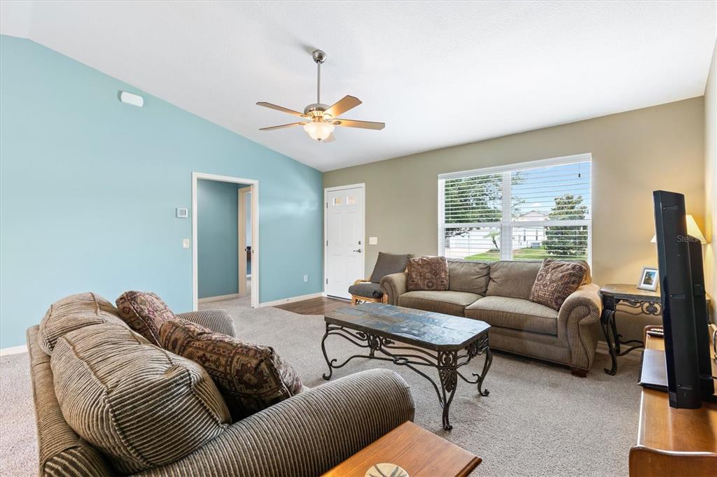 A living room features a ceiling fan, two sofas, a coffee table, and blue walls — 712 SHELTON STREET, THE VILLAGES, FL