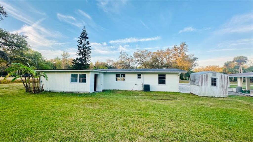 The exterior of a white, single-story house with a shed in a grassy backyard — 101 ELLISON AVENUE, NEW SMYRNA BEACH, FL