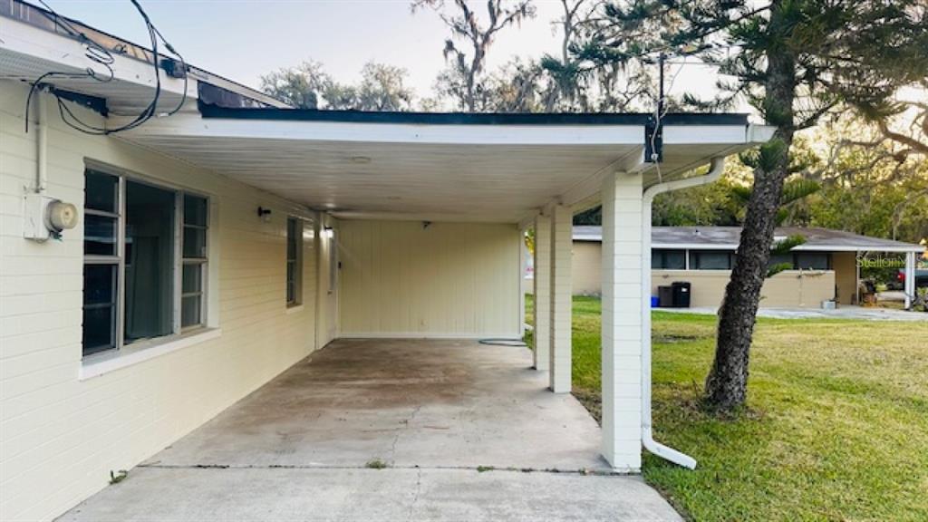 A concrete carport with white support pillars attached to the side of a house — 101 ELLISON AVENUE, NEW SMYRNA BEACH, FL