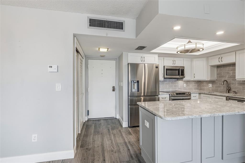 A modern kitchen features gray cabinetry, granite countertops, stainless steel appliances, and wood-look flooring — 5220 BRITTANY DR S UNIT 901, ST PETERSBURG, FL