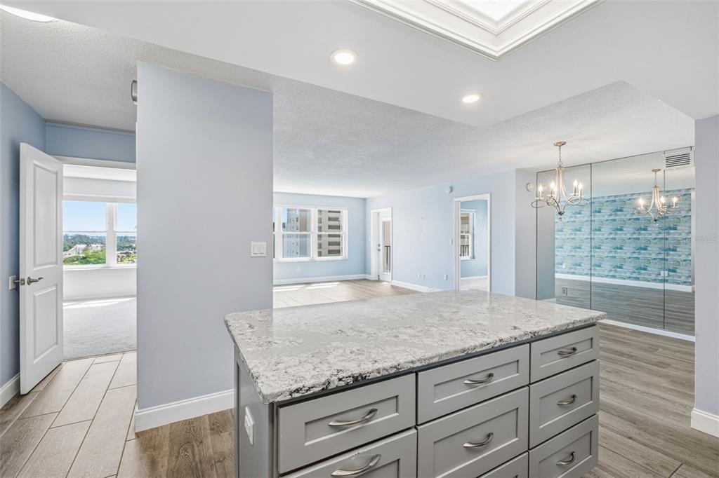 A kitchen island with gray cabinets and a granite countertop sits in a light-filled room — 5220 BRITTANY DR S UNIT 901, ST PETERSBURG, FL