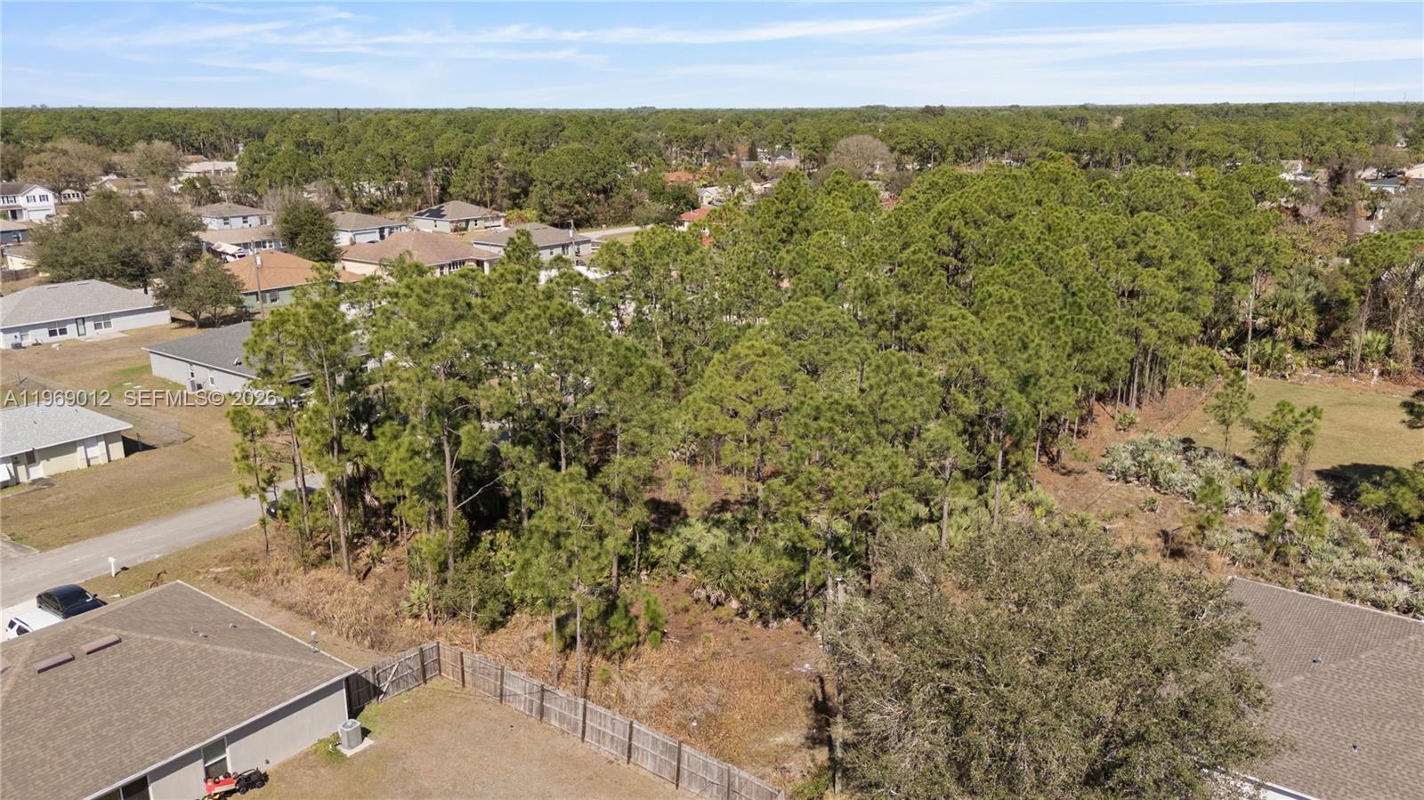 An aerial view shows a wooded vacant lot situated between residential houses and a street — 999 Cranberry Rd SE, Palm Bay FL 32909, PALM BAY, FL