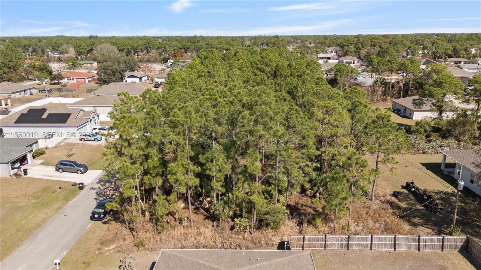 An aerial view shows a wooded lot situated between several residential houses and a fence — 999 Cranberry Rd SE, Palm Bay FL 32909, PALM BAY, FL