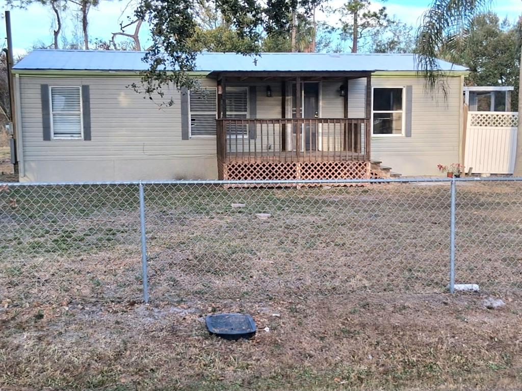A single-story manufactured home with a front porch sits behind a chain-link fence — 8013 FORMBY STREET, RIVERVIEW, FL