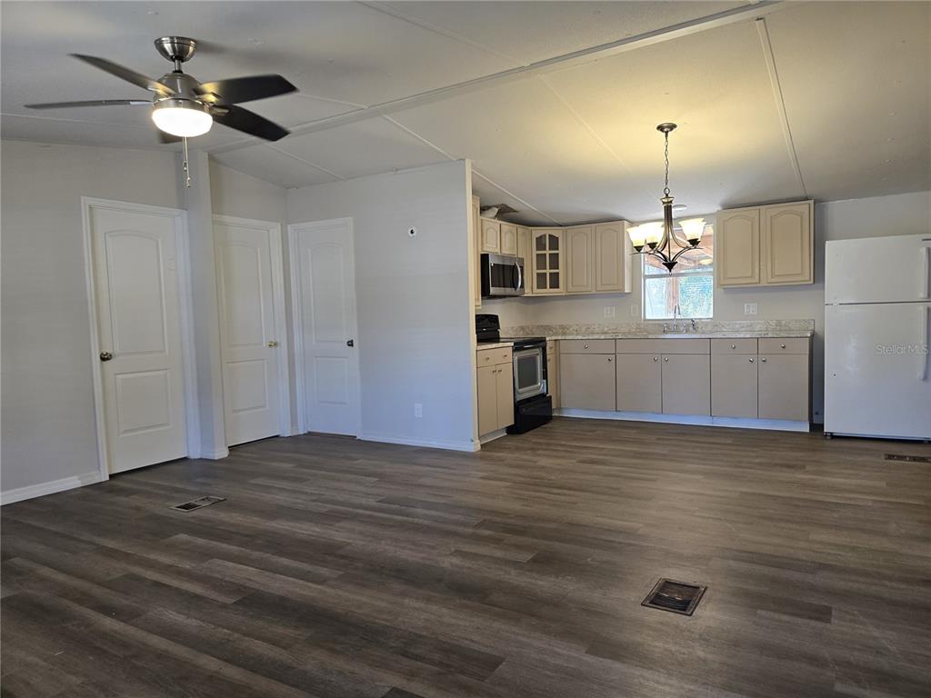 An open-concept kitchen and living area with light cabinets, wood-look flooring, and a ceiling fan — 8013 FORMBY STREET, RIVERVIEW, FL