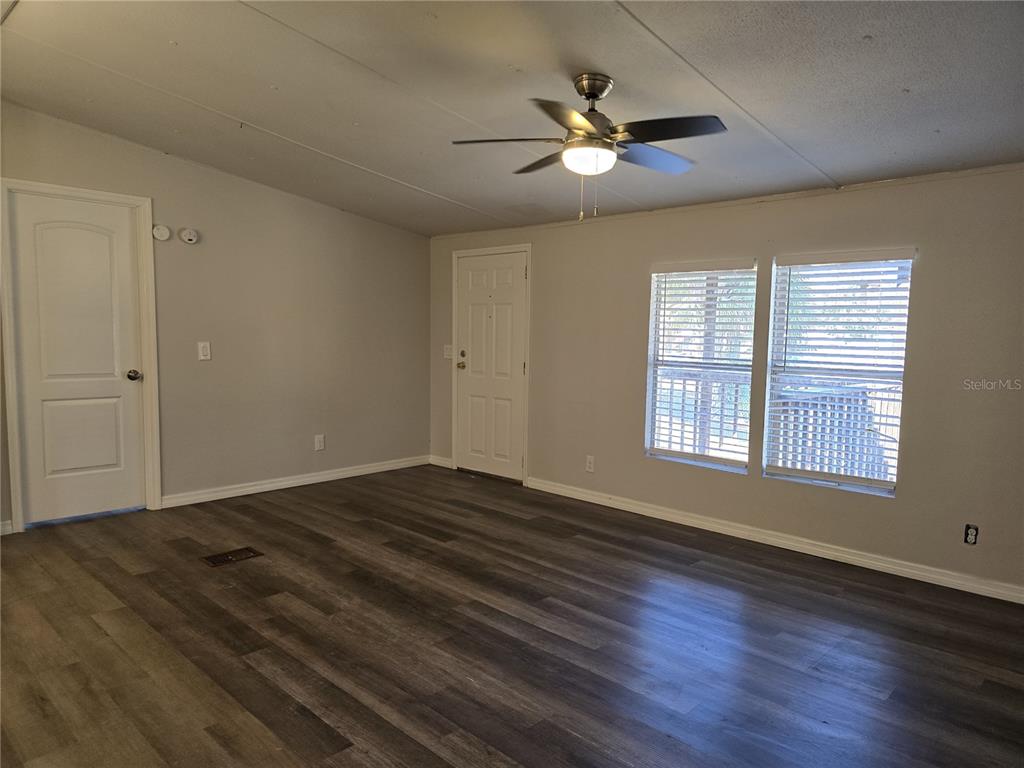 An empty room features gray walls, wood-look flooring, a ceiling fan, and two windows — 8013 FORMBY STREET, RIVERVIEW, FL