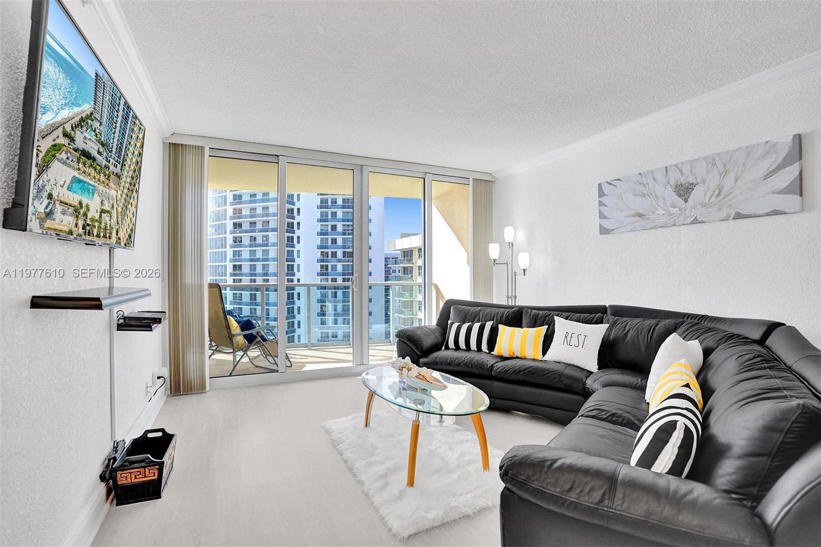 A living room features a black sectional sofa, glass coffee table, and balcony with city views — 2501 S Ocean Dr, Hollywood FL 33019, HOLLYWOOD, FL