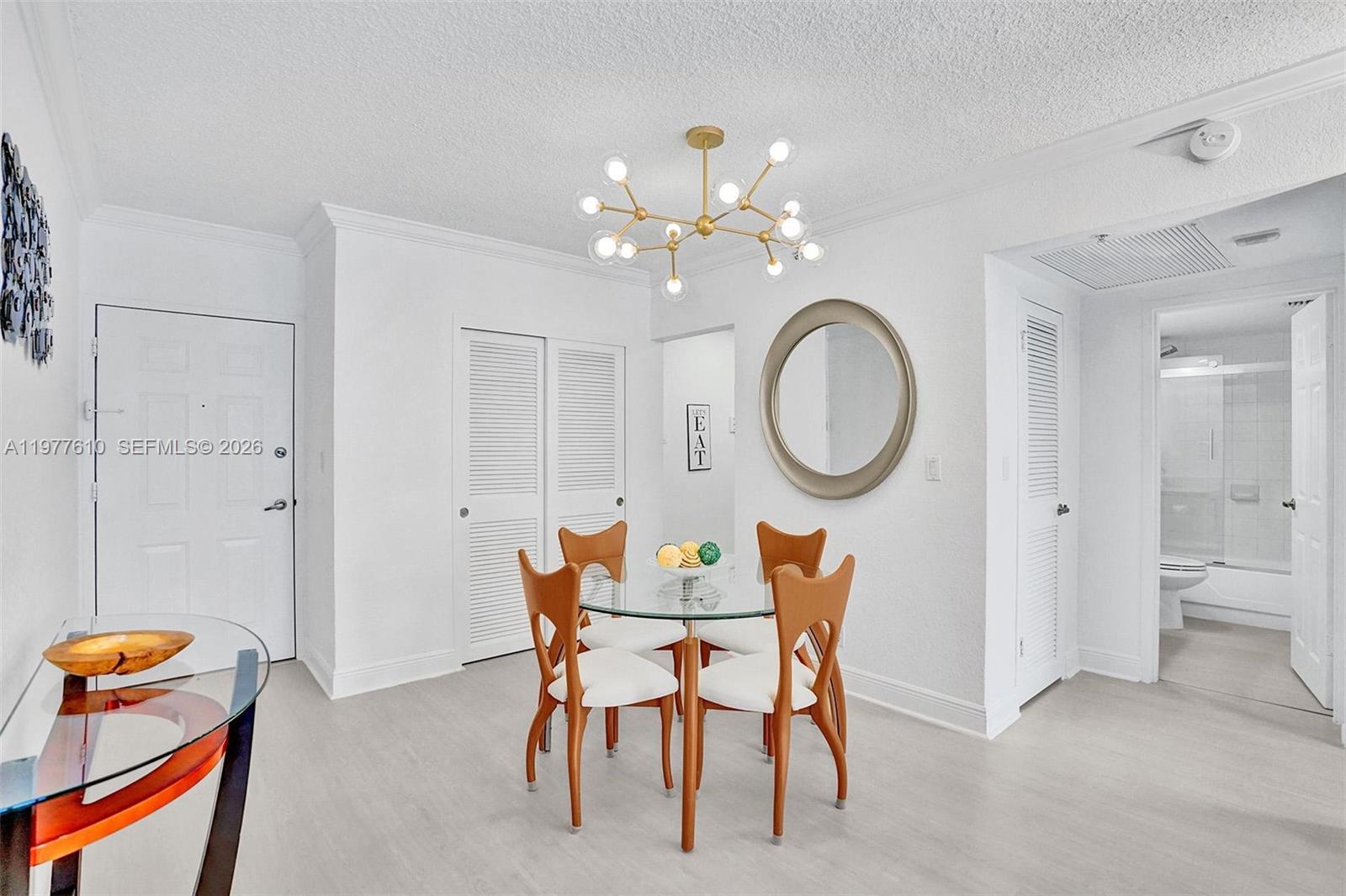 A dining area features a glass-topped table, four wooden chairs, and a modern gold chandelier — 2501 S Ocean Dr, Hollywood FL 33019, HOLLYWOOD, FL