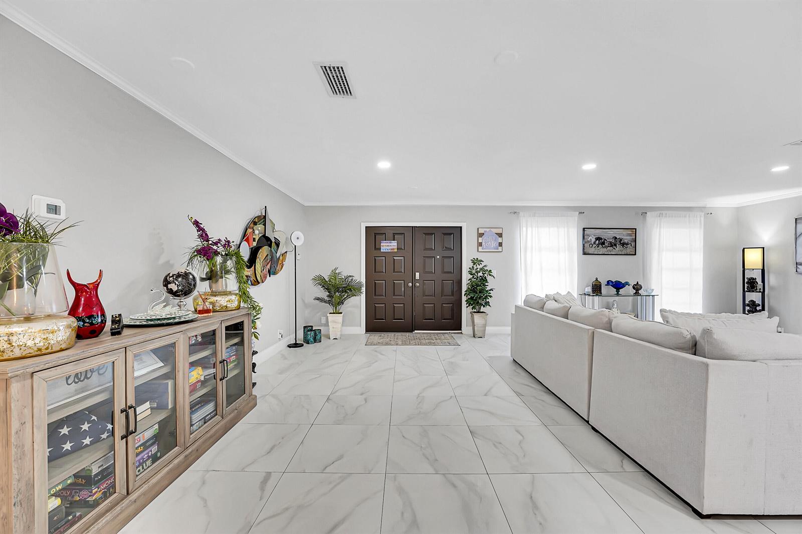 A spacious living room features white marble-look tile floors and a double front door entrance — 1618 The 12th Fairway, Wellington FL 33414, WELLINGTON, FL