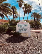 A white sign for Sunrise stands in a gravel garden surrounded by palm trees — 4141 S ATLANTIC AVENUE UNIT 406, NEW SMYRNA BEACH, FL