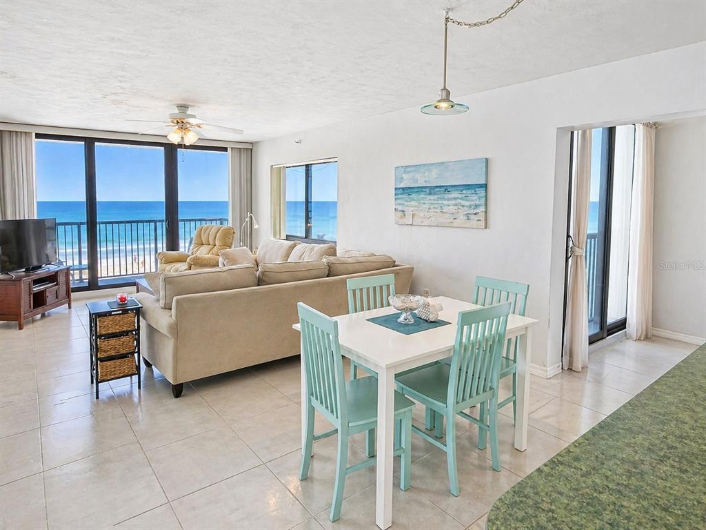 A living and dining area features tile floors, a beige sofa, and ocean views — 4141 S ATLANTIC AVENUE UNIT 406, NEW SMYRNA BEACH, FL