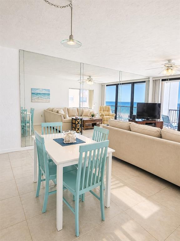 A dining area with a white table and turquoise chairs sits before a mirrored wall — 4141 S ATLANTIC AVENUE UNIT 406, NEW SMYRNA BEACH, FL