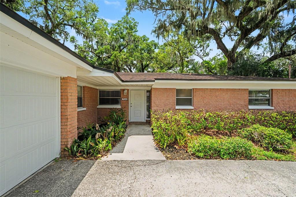 A single-story brick house features a white garage door and a concrete walkway — 714 COULTER PLACE, BRANDON, FL