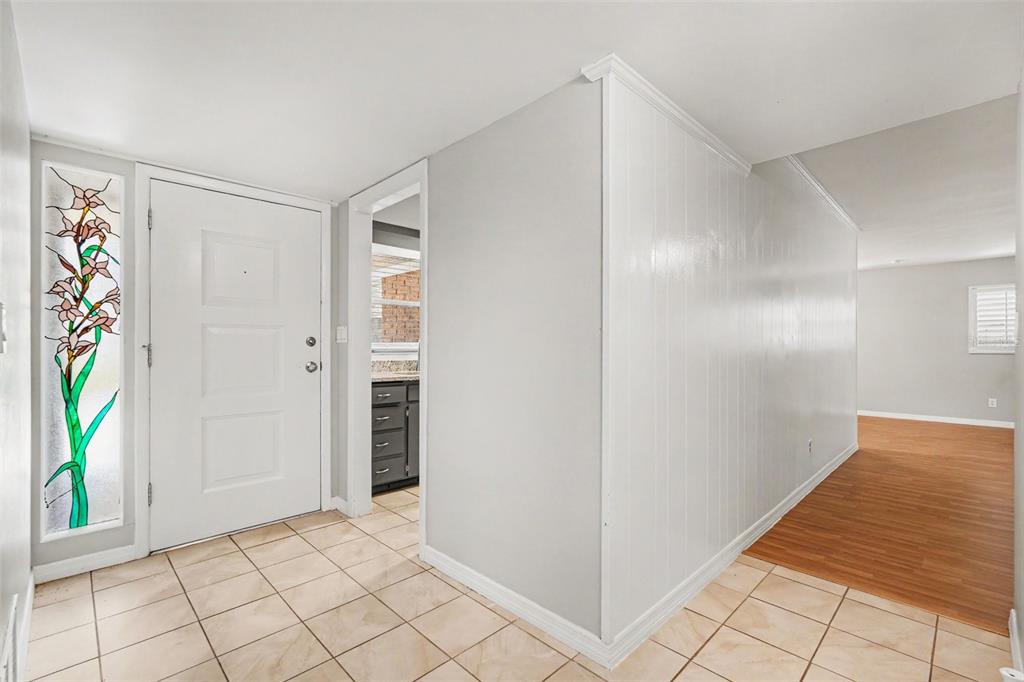 An entryway with tile flooring, a white front door, and a stained-glass sidelight window — 714 COULTER PLACE, BRANDON, FL