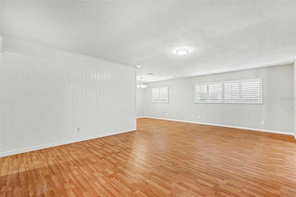 A spacious room with light wood-look flooring, white walls, and white plantation shutters — 714 COULTER PLACE, BRANDON, FL